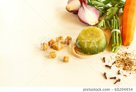 Frozen broth and herbs and seasonings on a wooden spoon, horizontally with space 68204934