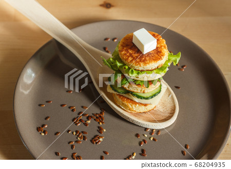 appetizer of mini pancakes with lettuce and cucumbers, served on a wooden spoon 68204935