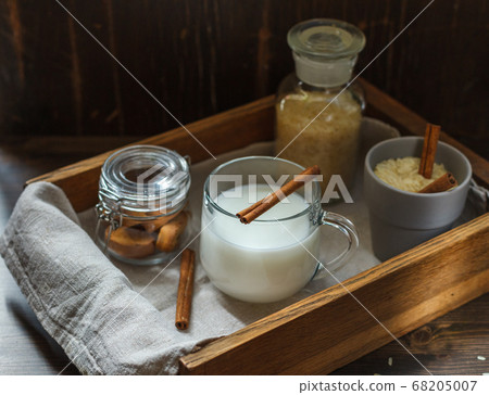 vegetarian rice milk in a glass Cup with a cinnamon stick on a wooden tray with crackers, low key vegetarian rice milk in a glass Cup with a cinnamon stick on a wooden tray with crackers, low key 68205007