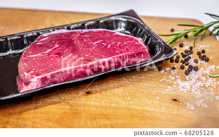 Beef steak in vacuum skin packaging and spices on wooden chopping board with copyspace 68205128