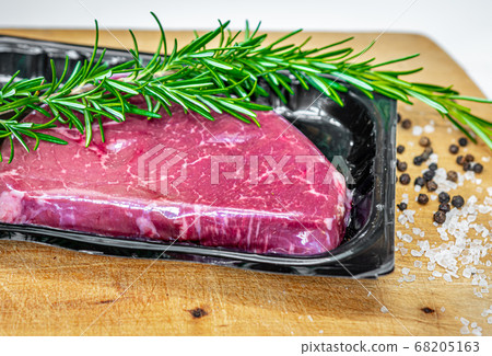 Beef steak in vacuum skin packaging and spices on wooden chopping board Beef steak in vacuum skin packaging and spices on wooden chopping board 68205163