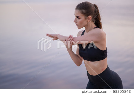 conceptual photo of a young girl stretching on the seashore at sunset conceptual photo of a young girl stretching on the seashore at sunset 68205848