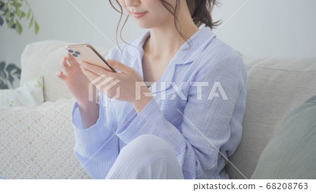 少婦在睡衣早晨的操作智能手機 68208763