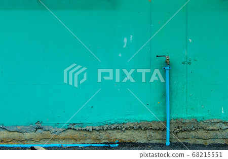 The brick wall is painted green and a faucet start damage. 68215551