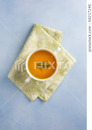 Bouillon in bowl on green textile on blue surface 68217246