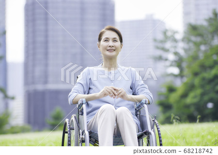Smiling senior woman sitting in a wheelchair outdoors 68218742
