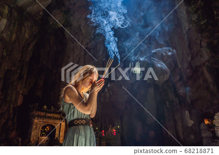 Young woman praying in a Buddhist temple holding incense Huyen Khong Cave with shrines, Marble mountains, Vietnam 68218871