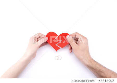 Female and male hands hold a broken heart on a Female and male hands hold a broken heart on a 68218908