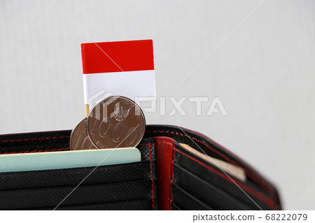Two coins of one thousand Rupiah with mini Indonesia flag stick on the black wallet. Two coins of one thousand Rupiah with mini Indonesia flag stick on the black wallet. 68222079