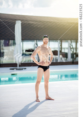 Man standing near the outdoor pool on sunny day. 68223525