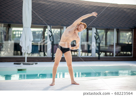 Focused young guy doing sports near the pool Focused young guy doing sports near the pool 68223564