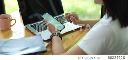 Female freelancer holding mock up smartphone while 68223628