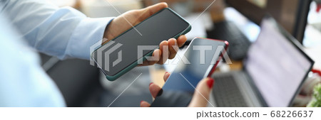 Two modern touch phones are held in hands of office. Two modern touch phones are held in hands of office. 68226637