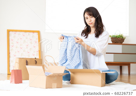 Dissatisfied young woman with clothes bought at an online shop Dissatisfied young woman with clothes bought at an online shop 68226737