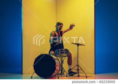 Young caucasian musician inspired performing on yellow background in neon light Young caucasian musician inspired performing on yellow background in neon light 68229000