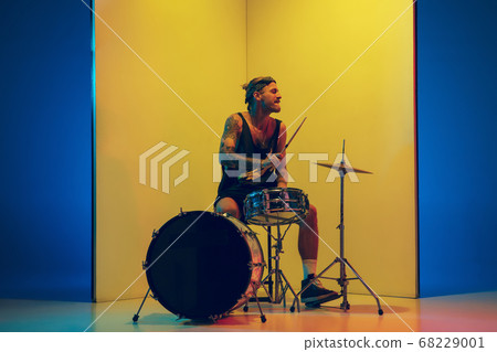 Young caucasian musician inspired performing on yellow background in neon light Young caucasian musician inspired performing on yellow background in neon light 68229001