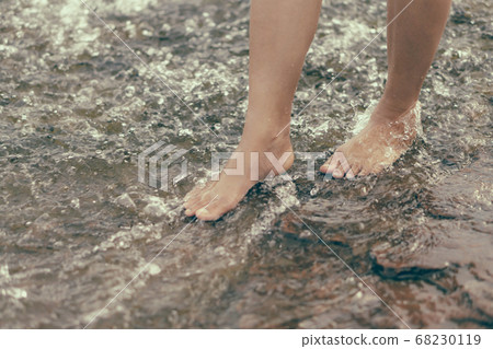 Woman legs relaxing with water on stone in the Woman legs relaxing with water on stone in the 68230119