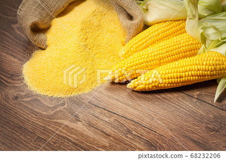 Ripe young sweet corn cob and cornmeal on wooden Ripe young sweet corn cob and cornmeal on wooden 68232206
