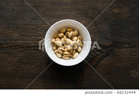 Pistachios in a small plate on a vintage wooden table. Pistachio is a healthy vegetarian protein nutritious food. Natural nuts snacks. Pistachios in a small plate on a vintage wooden table. Pistachio is a healthy vegetarian protein nutritious food. Natural nuts snacks. 68232444