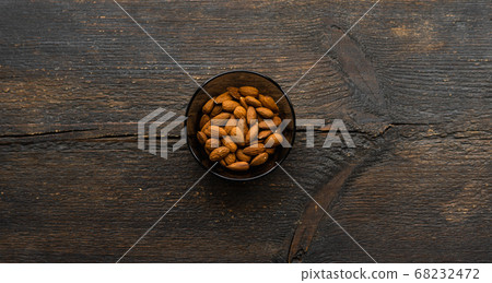 Almonds in a small plate on a vintage wooden table. Almond is a healthy vegetarian protein nutritious food. Natural nuts snacks. 68232472
