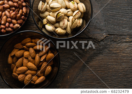Almond, pistachio and peanut in a small plates which standing on a black table. Nuts is a healthy vegetarian protein and nutritious food. Almond, pistachio and peanut in a small plates which standing on a black table. Nuts is a healthy vegetarian protein and nutritious food. 68232479