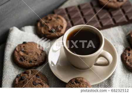Coffee cup with cookies and chocolate on wooden table background. Mug of black coffee with chocolate cookies. Fresh coffee beans. 68232512