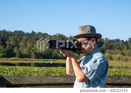 Asian man wearing sunglasses taking photos with a single lens reflex camera with a telephoto lens Vancouver Britte 68232535
