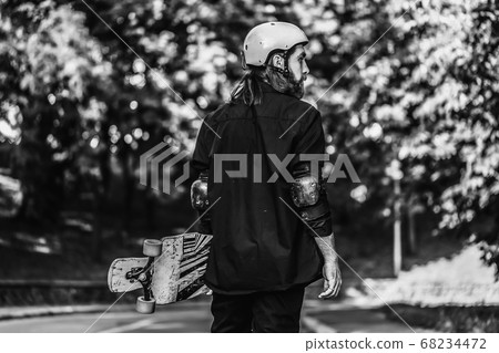 Black and white portrait of a bearded guy holding a skateboard, longboard. Black and white portrait of a bearded guy holding a skateboard, longboard. 68234472