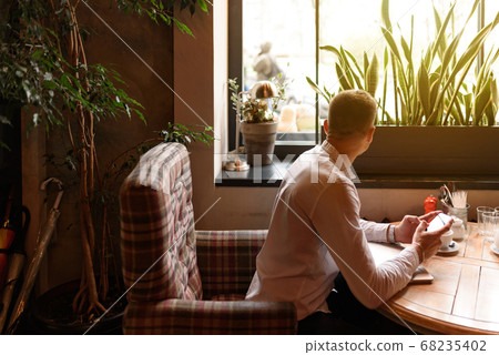 Man sitting at the table with smartphone in cafe 68235402