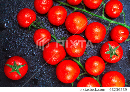 two ripe branch of cherry tomatoes in drops of Ross water on a black embossed table. copy space, top view, flat lay, horizontal orientation 68236289