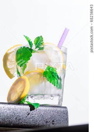 cocktail lemon, mint, ice in a rox glass on the edge of the bar counter white background. bot view, close up, vertical orientation cocktail lemon, mint, ice in a rox glass on the edge of the bar counter white background. bot view, close up, vertical orientation 68236643