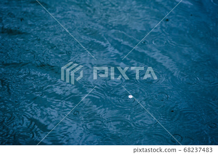 Waves created by raindrops falling on blue water Waves created by raindrops falling on blue water 68237483