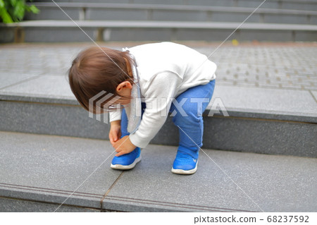 Toddlers practicing taking off shoes 68237592