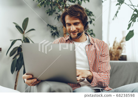 Young man wearing headset doing a video call by laptop 68238598