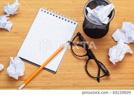 White note pad on a wooden table. Around the notepads lies lot crumpled paper 68238609