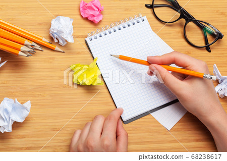 White note pad on a wooden table. Around the notepads lies lot crumpled paper 68238617