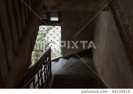 Dark stair descent in an old house with natural light coming from a barred window. The Mansion or Villa Bodega, Phnom Penh, Cambodia. 68238818
