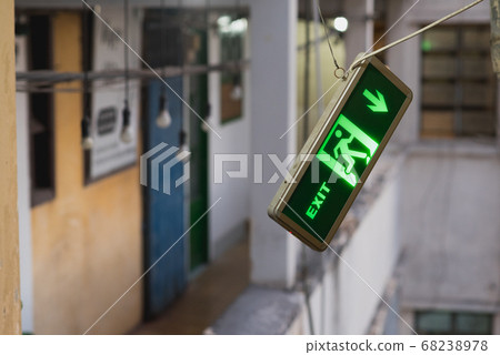 Sign Exit points into the direction of the space outside of the balcony railing as if it suggested to jump out of the building. A concept of despair, severe depression and suicidal behavior & thoughts 68238978
