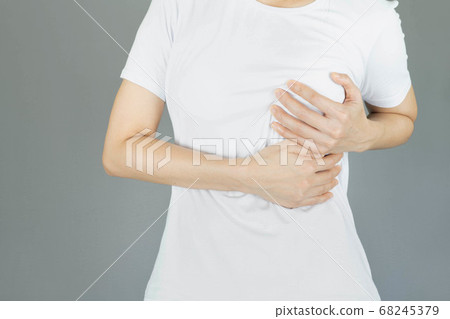 Woman hand checking lumps on her breast for signs of breast cancer on gray background, healthy lifestyle concept,healthy girl medical awareness cancer prevention concept 68245379