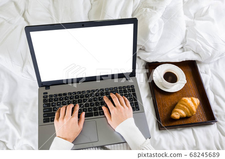 Selective focus,top view woman's hand holding typing on keyboard with a cup of coffee,croissant on bed in the morning,work online lifestyle relax at home ,working laptop in bedroom from home 68245689