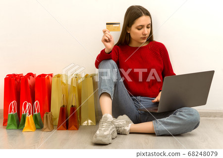 Young woman doing online shopping at home using 68248079