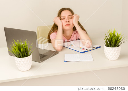 Tired overworked young intern woman working with a 68248080