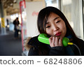 A woman calling with a public phone at the station 68248806
