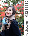 Woman posing in front of autumn leaves 68248812
