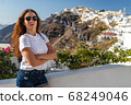 Happy smiling woman tourist traveling on luxury cruise in Mediterranean, Greece, Santorini. Female with folded arms, background architecture island sea sky 68249046