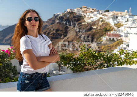 Happy smiling woman tourist traveling on luxury cruise in Mediterranean, Greece, Santorini. Female with folded arms, background architecture island sea sky 68249046
