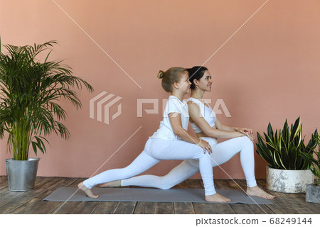 Smiling mother and daughter practicing yoga 68249144