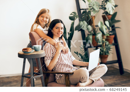 Carefree mother and daughter hugging at home 68249145