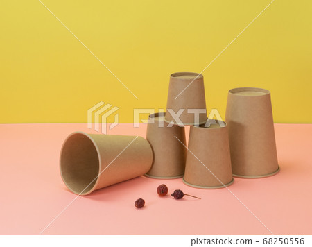 Disposable cups and berries of wild rose on yellow 68250556