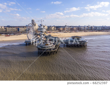 Pier with Ferris Wheel at Northern Sea Scheveningen Beach , located near the Hague city aerial drone footage. Popular Dutch beach resort Scheveningen With a clouds on the Sky in a day 68252397